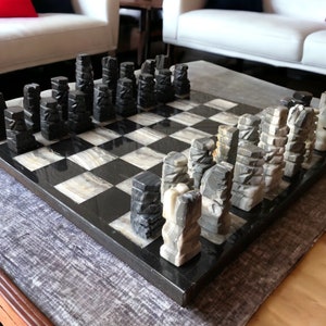 Peut inclure: Un jeu d'échecs en marbre noir et blanc avec des pièces sculptées. L'échiquier est en marbre noir et blanc et les pièces sont en marbre gris clair. Les pièces sont toutes dans le même style, avec un design géométrique sculpté.