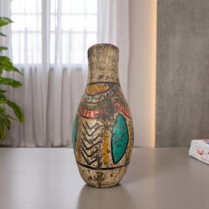 May include: A tall, decorative vase with a textured, aged appearance. The vase features colorful geometric patterns in red, yellow, and turquoise. The design includes a series of black zigzags and oval shapes.