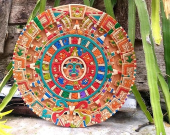 May include: A colorful, circular Aztec calendar with a central sun face surrounded by intricate designs and symbols. The calendar is painted in shades of red, orange, yellow, green, blue, and white.