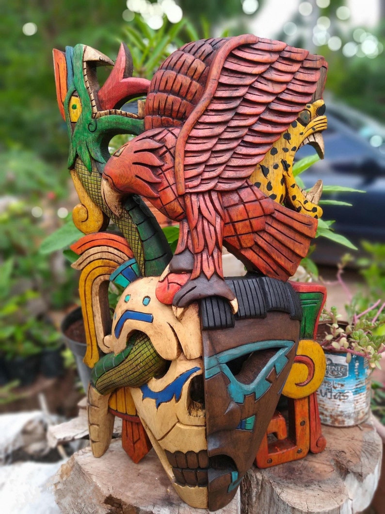 Peut inclure: Un masque en bois color&eacute; avec un visage de cr&acirc;ne, un jaguar et un oiseau aux ailes d&eacute;ploy&eacute;es. Le masque est peint dans des tons de rouge, vert, bleu, jaune et marron.