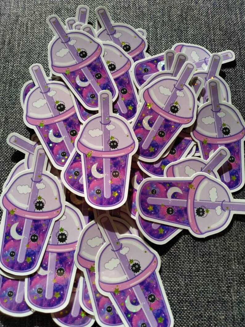 Puede incluir: Una colecci&oacute;n de pegatinas con un dise&ntilde;o de t&eacute; de burbujas morado y rosa. Las pegatinas tienen un fondo con tem&aacute;tica de galaxia con lunas, estrellas y un lindo personaje negro. Las tazas de t&eacute; de burbujas tienen tapa, pajita y acentos de nubes.