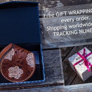 May include: A brown leather coin purse with floral tooled designs is displayed in a blue box. The box is open and the purse is visible. The text "Free GIFT WRAPPING with every order. Shipping worldwide with TRACKING NUMBER." is visible in the background.