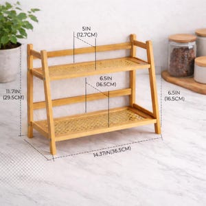 May include: A two-tiered bamboo shelf with woven rattan shelves. The shelf is 36.5 cm wide, 29.5 cm tall, and 12.7 cm deep. Each shelf is 16.5 cm apart. Suitable for kitchen or bathroom storage.