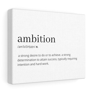 May include: A white canvas print with the word "ambition" in black text, followed by its phonetic pronunciation and definition. The definition reads: "a strong desire to do or to achieve. a strong determination to attain success, typically requiring intention and hard work."