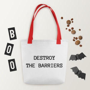 K&ouml;nnte beinhalten: Wei&szlig;e Einkaufstasche mit roten Henkeln und dem Text "DESTROY THE BARRIERS" in Schwarz gedruckt. Zwei schwarze Papierflederm&auml;use befinden sich auf beiden Seiten der Tasche.