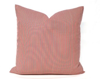 May include: Red and white striped throw pillow with a simple design. The pillow is made of a soft, comfortable fabric and is perfect for adding a touch of color to any room.