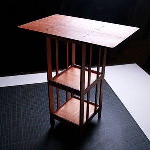 Puede incluir: Una estantería de madera con dos estantes y una superficie superior. La estantería está hecha de madera marrón oscura y tiene un diseño simple y rectangular.