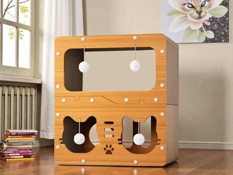 May include: A wooden cat house with a light brown finish. The house has two levels, with cat-shaped cutouts and hanging toy balls. The design includes a paw print and a large rectangular opening. White circular accents are placed around the edges.
