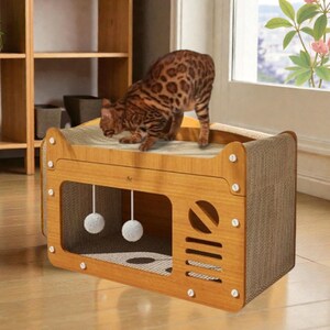 May include: A wooden cat house with a scratching surface on top and a playful design. The cat house has a rectangular shape with a brown finish, a cut-out window, and two hanging pom-poms. A brown and tan spotted cat is standing on top.