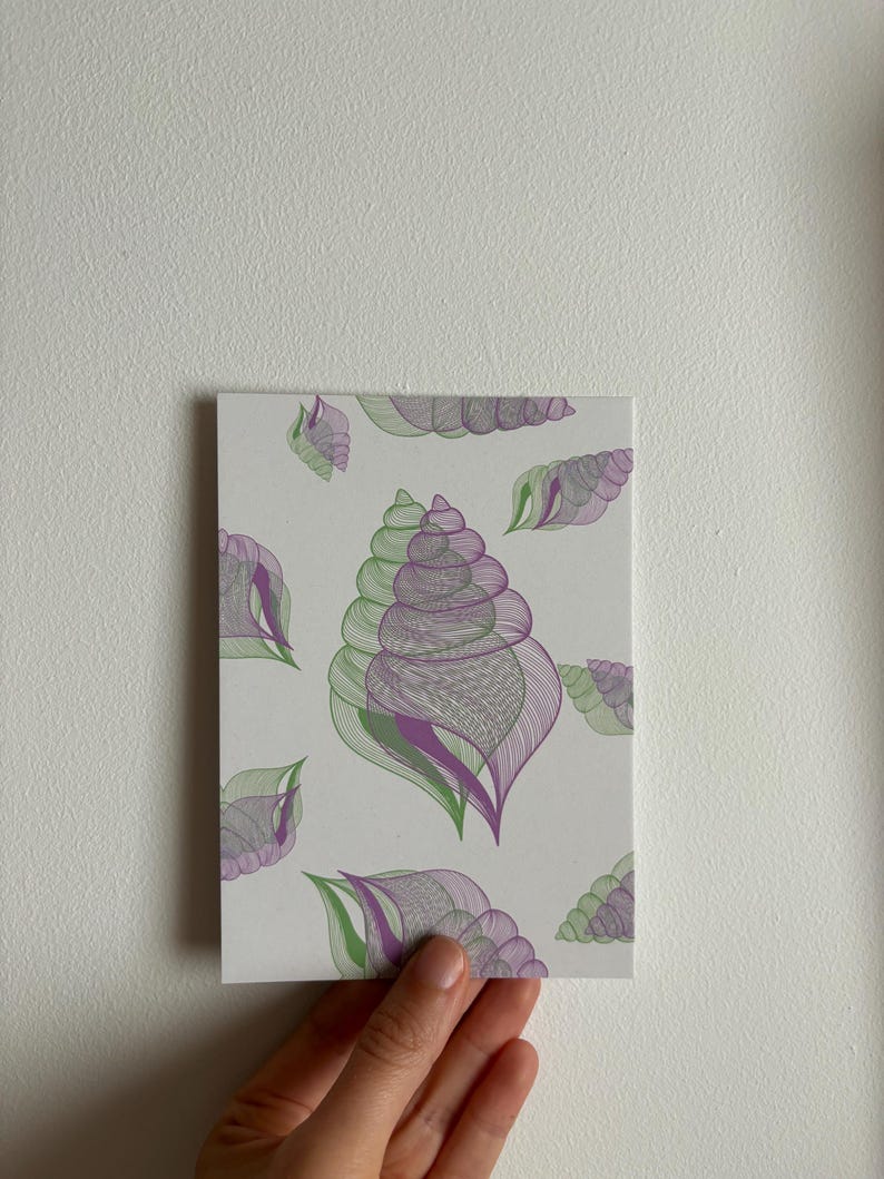 May include: A white card with a purple and green seashell pattern.