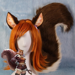 May include: A brown and white furry tail with a pair of brown and pink furry ears attached to a red wig. The wig is on a mannequin head.