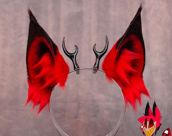 May include: Red and black faux fur devil ears headband with black horns. The headband is on a clear stand. The text '@tsukimimi_shop' is on the stand.