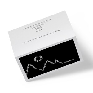 Op de afbeelding: Een zwart-witte afbeelding van een fietsketting die een bergketen vormt met een fietskettingwiel als zon.