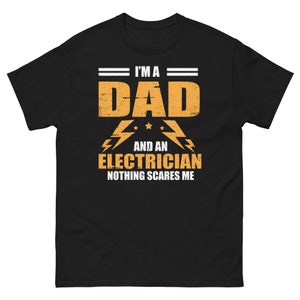 Puede incluir: Camiseta negra con un gráfico amarillo que dice "Soy un papá y un electricista Nada me asusta".