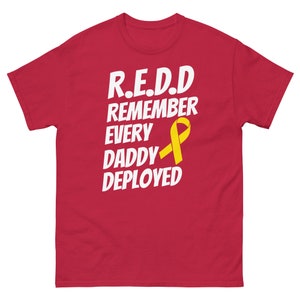 Könnte beinhalten: Rotes T-Shirt mit dem weißen Text "R.E.D.D. REMEMBER EVERY DADDY DEPLOYED" und einer gelben Schleife. Das T-Shirt hat einen Rundhalsausschnitt und kurze Ärmel.