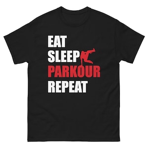 May include: Black t-shirt with white text that reads "Eat Sleep Parkour Repeat". A red silhouette of a person doing a parkour move is between the words "Sleep" and "Parkour".