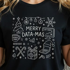 May include: Black t-shirt with a white graphic design featuring a Christmas tree, ornaments, snowflakes, and a laptop wearing a Santa hat. The text "MERRY DATA-MAS" is displayed prominently.