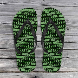 May include: A pair of black flip-flops with a green and black binary code pattern.