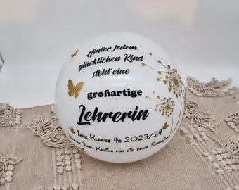 May include: White ceramic sphere with gold butterflies and dandelion designs. The text reads "Hinter jedem glücklichen Kind steht eine großartige Lehrerin. Ihre Klasse 4b 2023/24 Frau Kozina für die tolle Schnu"