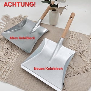 May include: Two metal dustpans with wooden handles. The dustpans are silver and have a rectangular shape. The handles are light brown. The text "ACHTUNG!" is at the top of the image. The text "Altes Kehrblech" and "Neues Kehrblech" are also visible.