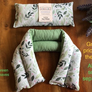 May include: A set of two eye pillows and a neck wrap. The items are white with a green leaf pattern and a solid green backing. The eye pillow has a tag that reads "Soothing Eye Pillow". The neck wrap is a U-shape.