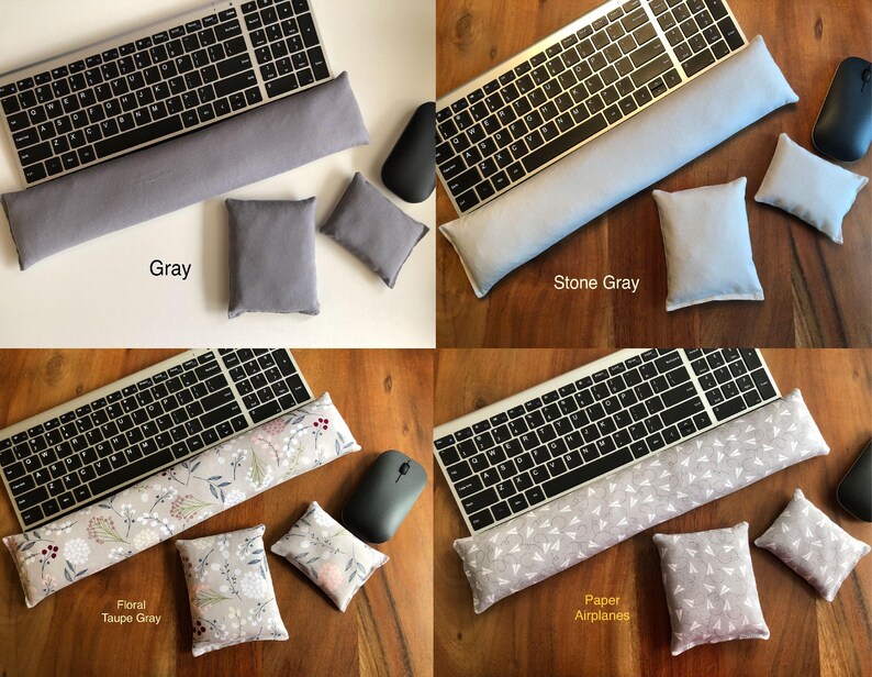 May include: A collection of keyboard wrist rests and matching mouse pads in various colors and patterns. The options include solid gray, stone gray, floral taupe gray, and a paper airplane design. Each set includes a keyboard rest, a mouse pad, and two small square pads.