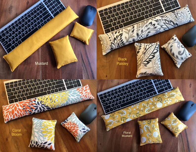 May include: Four keyboard wrist rests and matching small pillows in various colors and patterns. The options include mustard yellow, black paisley, coral bloom, and floral mustard. Each set includes a keyboard, mouse, wrist rest, and two pillows.