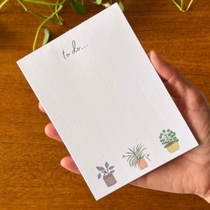 May include: White notepad with the text "to do..." at the top. The notepad has three small illustrations of potted plants at the bottom.