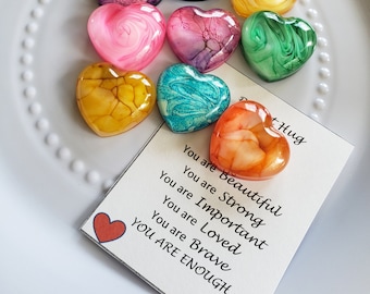 May include: Eight colorful heart-shaped resin ornaments with swirling patterns. A card with the text "You are Beautiful, You are Strong, You are Important, You are Loved, You are Brave, YOU ARE ENOUGH" and a red heart at the bottom.