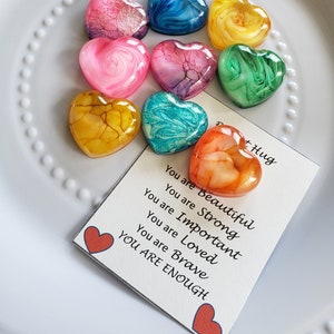 May include: Eight colorful heart-shaped resin ornaments with swirling patterns. A card with the text "You are Beautiful, You are Strong, You are Important, You are Loved, You are Brave, YOU ARE ENOUGH" and a red heart at the bottom.