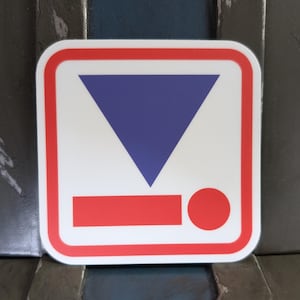 May include: A white square sticker with a red border. Inside the square is a blue triangle pointing down, a red rectangle, and a red circle.