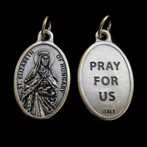 May include: Silver metal religious medal featuring an image of Saint Elizabeth of Hungary on one side and the words "Pray for Us" on the reverse. The medal is made in Italy.