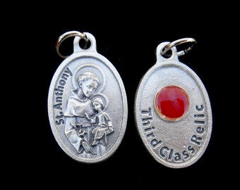 May include: Silver oval pendant with a depiction of Saint Anthony holding a baby. The back of the pendant reads "Third Class Relic".