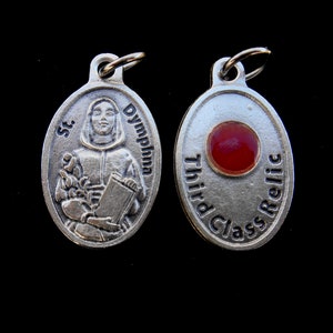 May include: Silver oval pendant with a depiction of Saint Dymphna on one side and the words "Third Class Relic" on the other side. The pendant has a red glass insert.