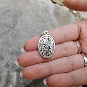 Pu&ograve; includere: Pendente ovale in argento con una rappresentazione di Ges&ugrave; sulla croce circondato da figure.
