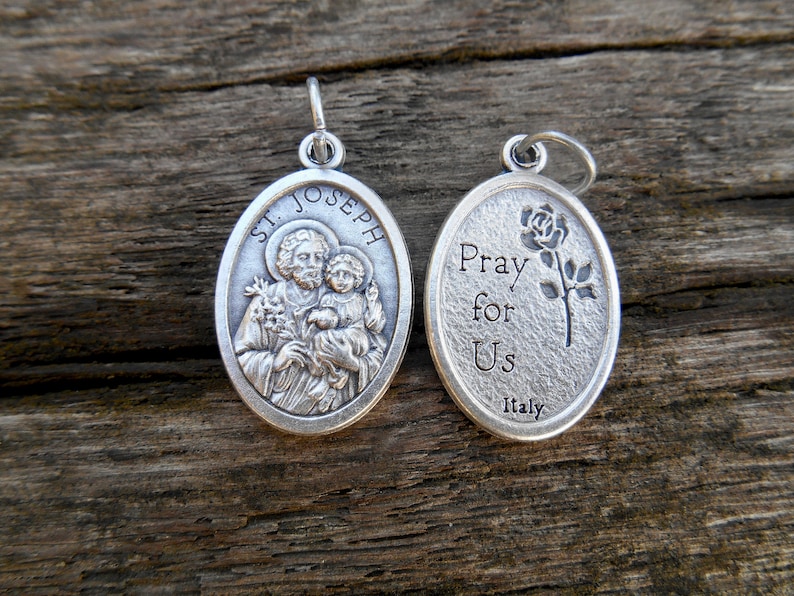 May include: Silver oval pendant with a depiction of Saint Joseph holding baby Jesus on one side and the words "Pray for Us Italy" on the other side.