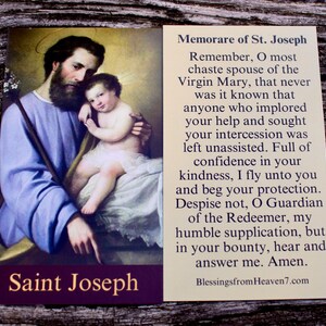 May include: A rectangular prayer card featuring a painting of Saint Joseph holding the infant Jesus on the left side, with the text Saint Joseph at the bottom. The right side contains the Memorare of St. Joseph prayer in black text on cream.