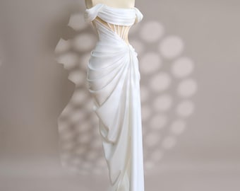 May include: A white off-the-shoulder gown with a fitted bodice and a flowing skirt. The bodice features a corset-like design with vertical straps.