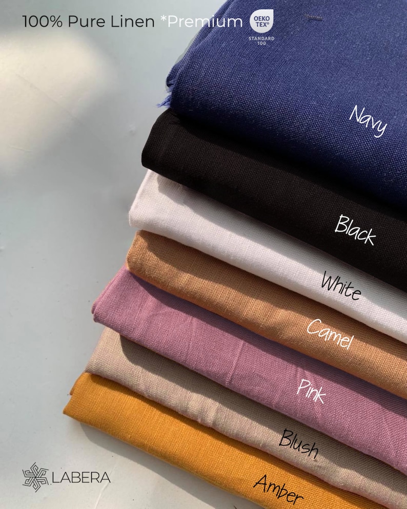 May include: A stack of eight fabric swatches in different colors, including navy, black, white, camel, pink, blush, and amber. The fabric is 100% pure linen and is labeled as "Premium". The Oeko-Tex Standard 100 logo is visible on the top swatch.