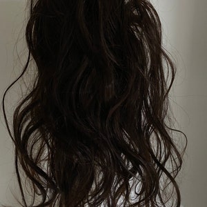May include: A long, dark brown hair extension with a wavy texture. The hair is loose and flowing, creating a natural look.