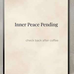 Könnte beinhalten: Ein rechteckiges Wandbild in einem dünnen schwarzen Rahmen mit cremefarbenem Hintergrund, auf dem der schwarze Text Inner Peace Pending und der kleinere Text check back after coffee mittig platziert sind.