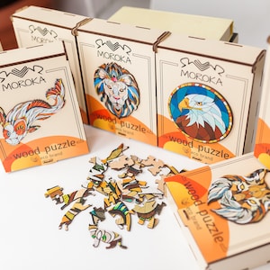 Peut inclure: Assortiment de puzzles en bois avec des illustrations d'animaux colorés. Les puzzles sont emballés dans des boîtes portant le nom de la marque "MOROKA" et les mots "puzzle en bois" imprimés dessus.