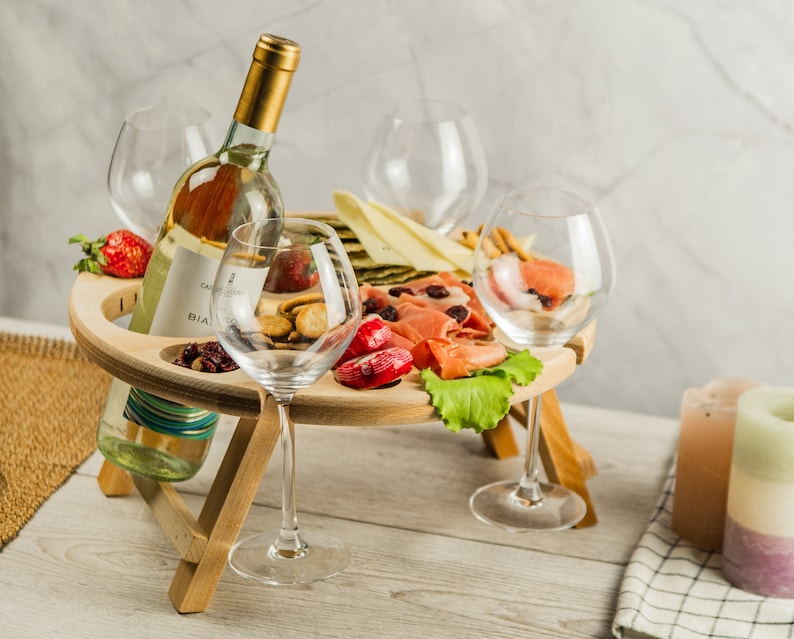 K&ouml;nnte beinhalten: Ein Holztablett mit einer Flasche Wei&szlig;wein, vier Weingl&auml;sern und einer Auswahl an Snacks, darunter K&auml;se, Cracker und Obst. Das Tablett ist so konzipiert, dass es eine Flasche Wein und vier Gl&auml;ser aufnehmen kann, was es perfekt f&uuml;r die Unterhaltung von G&auml;sten macht.