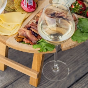 K&ouml;nnte beinhalten: Ein Holztablett mit eingebautem St&auml;nder, gef&uuml;llt mit K&auml;se, Crackern, Prosciutto, Mandeln und Erdbeeren. Ein Glas Wei&szlig;wein steht auf dem Tablett.