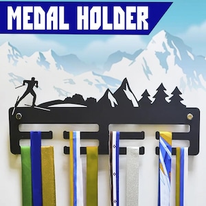 May include: Black metal medal holder with a silhouette of a cross-country skier in front of a mountain range. The holder has 8 slots for hanging medals.  The text "MEDAL HOLDER" is at the top of the holder.