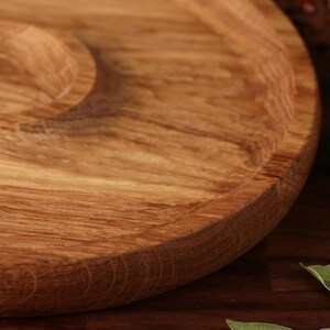 May include: A round wooden serving tray with a raised edge and a smooth, natural wood finish.