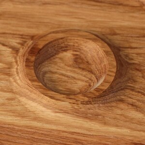 May include: Close-up of a wooden serving tray with a circular indentation. The tray is made of light brown wood with a natural grain pattern.