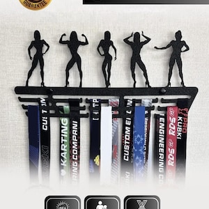 May include: A black galvanised steel medal hanger featuring five silhouette figures of athletes in various poses. The rack includes multiple horizontal bars for hanging ribbons and medals, with text labels including "SATISFACTION GUARANTEE", "GIFT IDEA", "ADULT AND CHILD", and "FITS UP TO 50 MEDALS".
