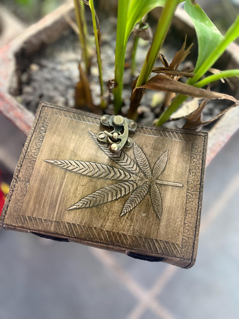May include: A brown leather journal with a brass clasp and a leaf design embossed on the cover.