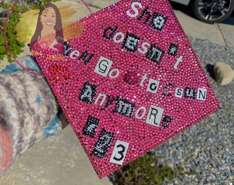 May include: Pink graduation cap covered in rhinestones with the text "She doesn't go to class anymore" in black letters.
